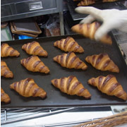 焼きあがったばかりのクロワッサン。待ちわびていたお客様のトレーに、スタッフが丁寧にのせてくれる。