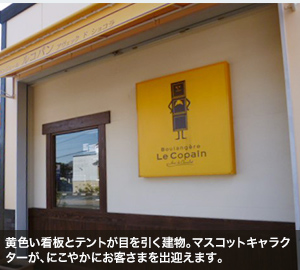 黄色い看板とテントが目を引く建物。マスコットキャラクターが、にこやかにお客さまを出迎えます。