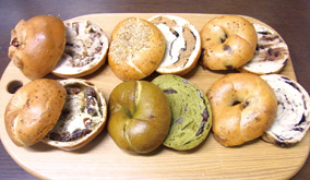 「tecona bagel works」の人気商品たち。左上から時計回りに「ふか」メープルペカンナッツ、「むぎゅ」ツナ、「もち」チョコオレンジ、「もち」ブルーベリー、「むぎゅ」抹茶大納言、「ふか」紅茶ラムレーズン（220円前後）